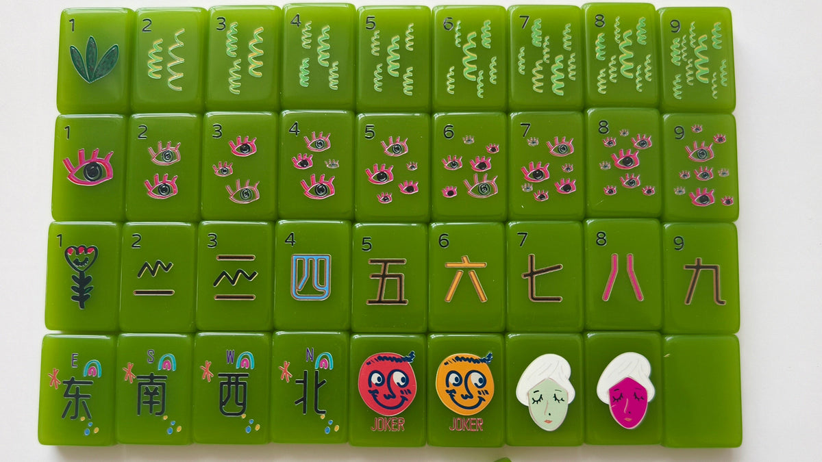 Green mahjong tiles arranged in a grid on a white background, with a matching green tile placed to the left. The tiles feature characters and colorful illustrations.