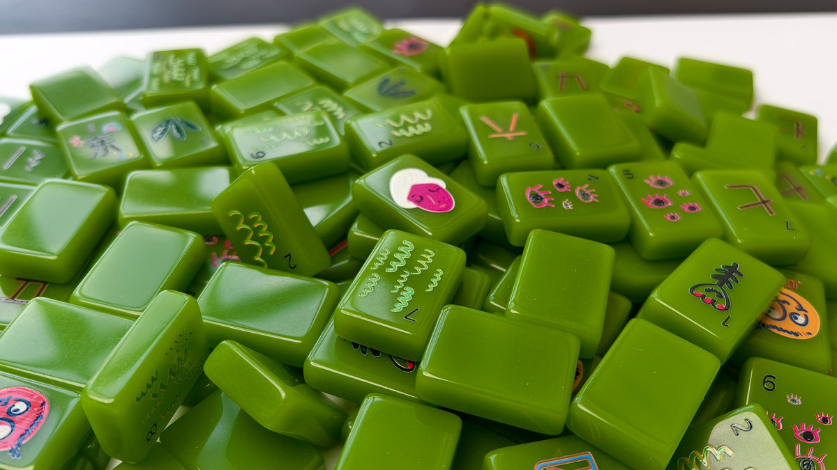 A pile of bright green mahjong tiles with various characters and symbols printed on them, filling almost the entire frame.