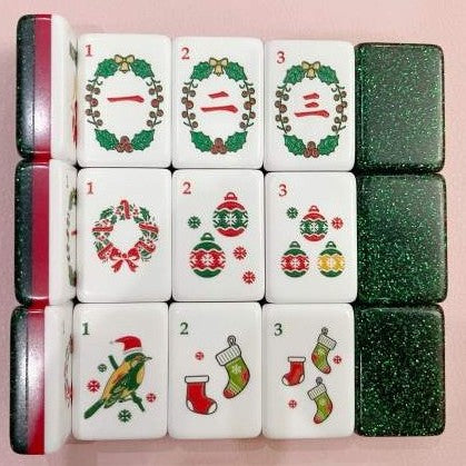 Close-up of Christmas American Mahjong tiles with wreaths, ornaments, stockings, a holiday bird and green glitter backs